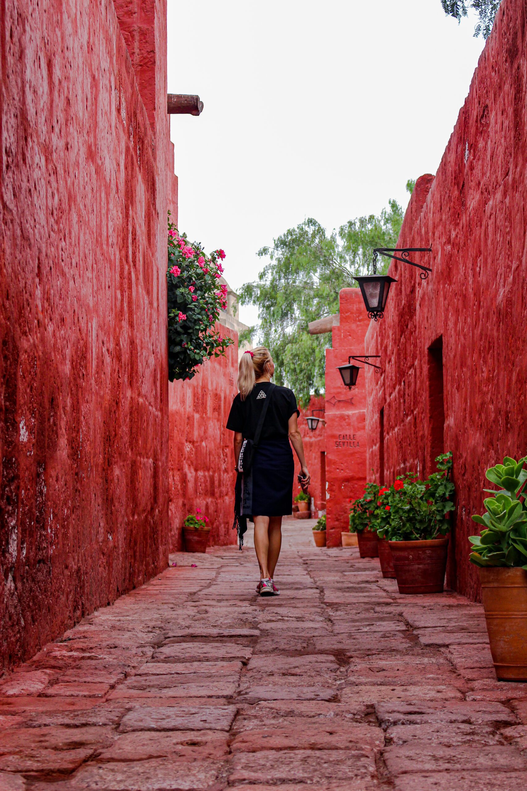 blond pige går ved røde mure i Santa Catalina Monastery Peru 